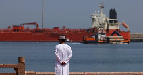 A man stands near the waterfront as a vessel sits at anchor, amid the U.S.-Israeli conflict with Iran, at Sultan Qaboos Port in Muscat, Oman, March 16, 2026. (Reuters Photo)