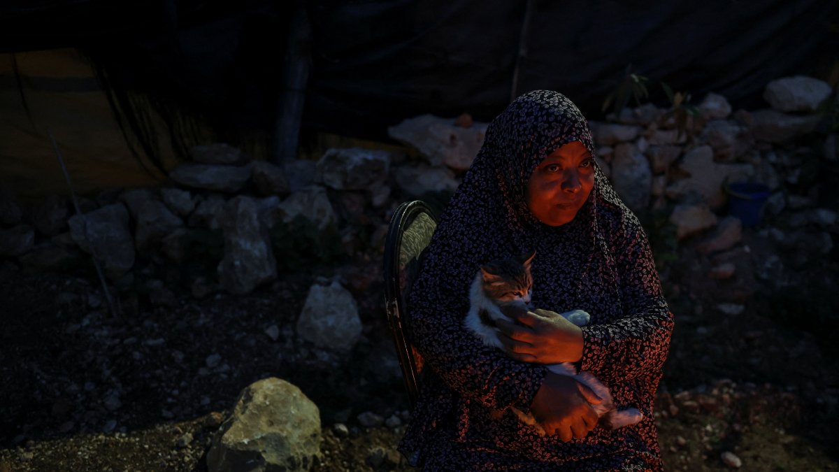 Areej Ghanem holds a cat outside a shack near Tulkarm, West Bank, Palestine, Feb. 16, 2026. (Reuters Photo)