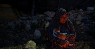 Areej Ghanem holds a cat outside a shack near Tulkarm, West Bank, Palestine, Feb. 16, 2026. (Reuters Photo)