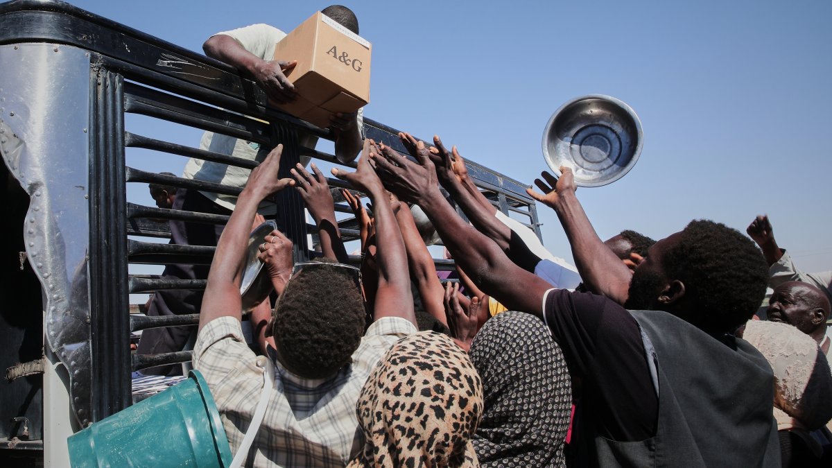 Sudanese families displaced from el-Fasher reach out as aid workers distribute food supplies at the newly established el-Afadh camp in al Dabbah, Sudan, Nov. 16, 2025. (AP Photo)