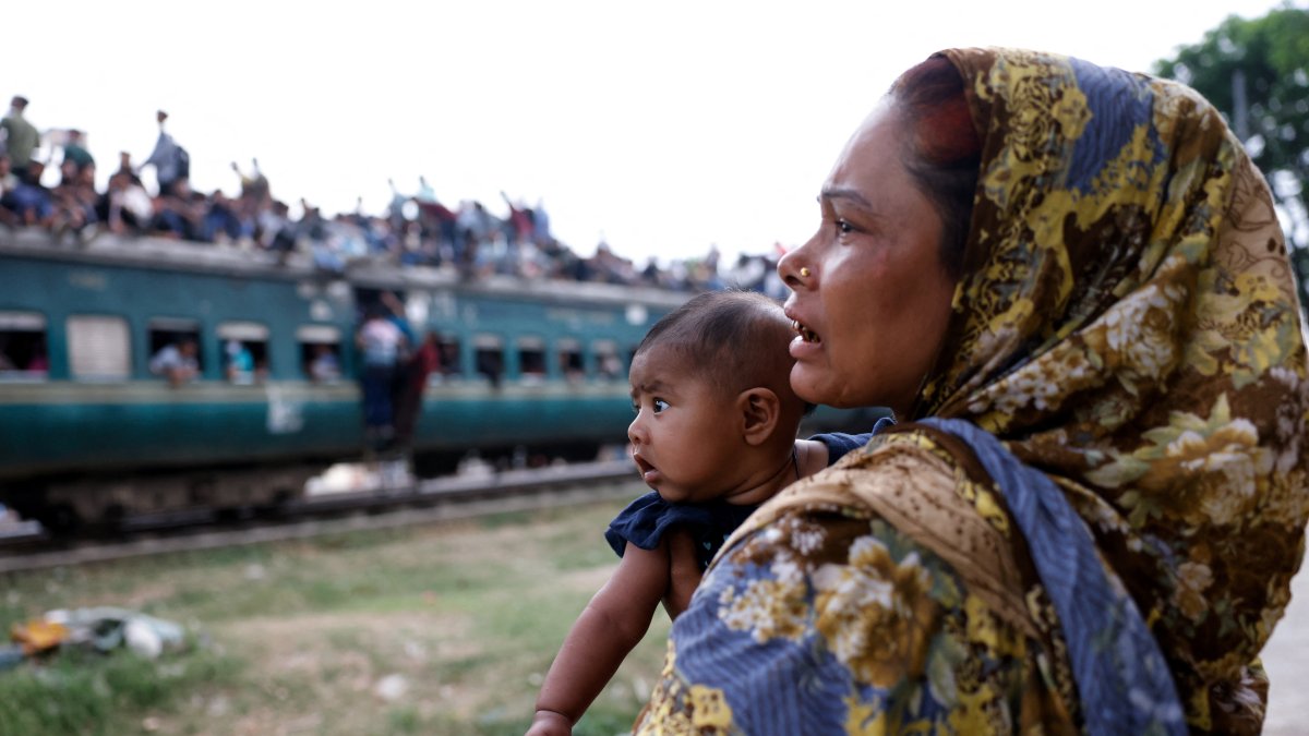 A woman with a child watches people travel on an overcrowded train, as they leave Dhaka to celebrate Eid al-Fitr, which marks the end of the Muslim holy fasting month of Ramadan, at Tongi Railway Station in Gazipur, Bangladesh, March 18, 2026. (Reuters Photo)