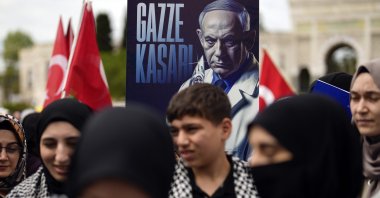 A demonstrator holds a poster of Israeli Prime Minister Benjamin Netanyahu with Turkish words that read, "Gaza Butcher" during a pro-Palestinian protest, Istanbul, Türkiye,  April 21, 2024. (AP Photo)
