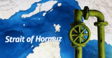 A map showing the Strait of Hormuz and a 3D-printed oil pipeline are seen in this illustration, March 23, 2026. (Reuters Photo)