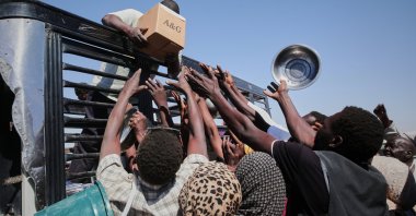 Sudanese families displaced from el-Fasher reach out as aid workers distribute food supplies at the newly established el-Afadh camp in al Dabbah, Sudan, Nov. 16, 2025. (AP Photo)