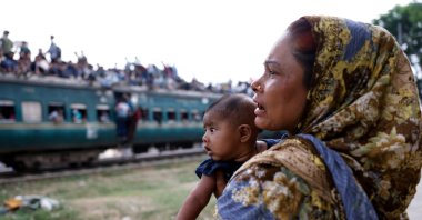 A woman with a child watches people travel on an overcrowded train, as they leave Dhaka to celebrate Eid al-Fitr, which marks the end of the Muslim holy fasting month of Ramadan, at Tongi Railway Station in Gazipur, Bangladesh, March 18, 2026. (Reuters Photo)