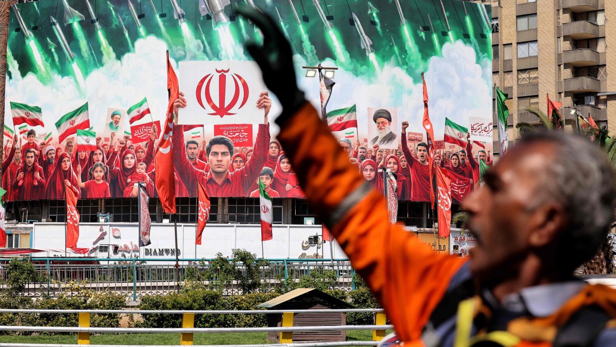 A municipal worker gestures near a large political banner at a square in Tehran, Iran, April 6, 2026. (AFP Photo)