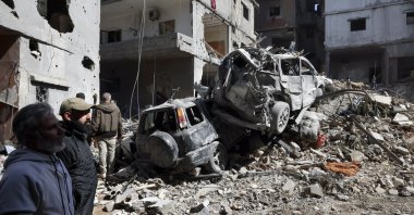 People look at a damaged car and a building following an Israeli strike near the Rafik Hariri University Hospital (RHUH), Jnah District, Beirut, Lebanon, April 6, 2026. (EPA Photo)