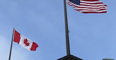 Canadian and American flags flutter against a blue sky in Maple, Ontario, Canada, Feb. 6, 2026. (AFP File Photo)