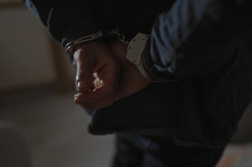 A suspect is handcuffed by police after his arrest. (Shutterstock Photo) 