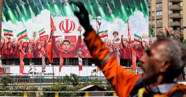 A municipal worker gestures near a large political banner at a square in Tehran, Iran, April 6, 2026. (AFP Photo)