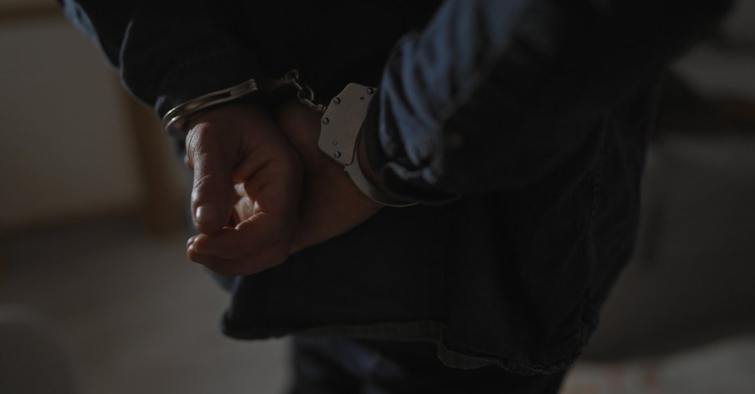 A suspect is handcuffed by police after his arrest. (Shutterstock Photo) 