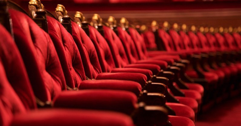 Rows of plush red velvet opera chairs with ornate gold trim. (Shutterstock Photo)