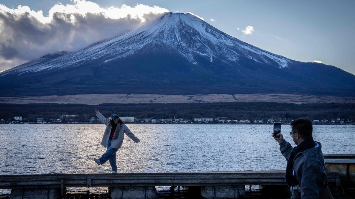 People take photographs with Mount Fuji at Lake Yamanakako, Yamanashi prefecture, Japan, Dec. 5, 2025. (AFP Photo)