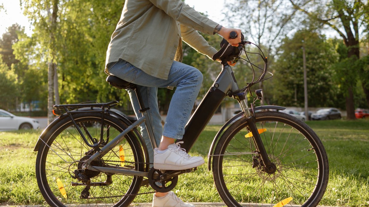 A person rides an electric bike on a path in a park. (Shutterstock Photo)