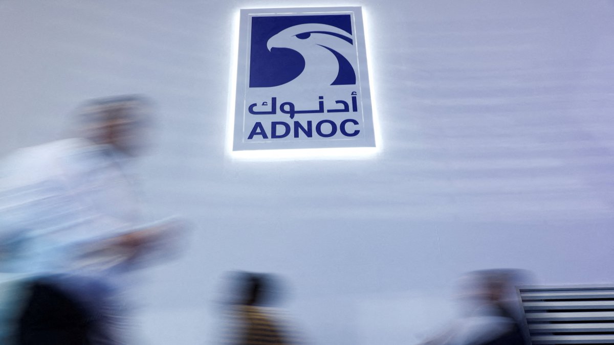 People walk past a logo of Abu Dhabi National Oil Company (ADNOC) during the annual energy industry event Abu Dhabi International Petroleum Exhibition and Conference (ADIPEC), Abu Dhabi, UAE, Nov. 3, 2025. (Reuters Photo)