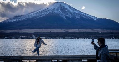 People take photographs with Mount Fuji at Lake Yamanakako, Yamanashi prefecture, Japan, Dec. 5, 2025. (AFP Photo)