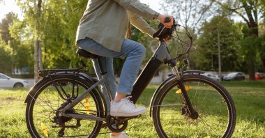 A person rides an electric bike on a path in a park. (Shutterstock Photo)