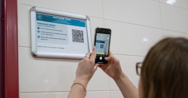 A woman scans a QR code to provide real-time feedback on hospital services, Istanbul, Türkiye, April 1, 2026. (AA Photo)