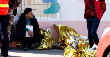 A man sits next to rescue units after an attempt to illegally cross the English Channel turned tragic, in Equihen-Plage, northern France, April 9, 2026. (AFP Photo)