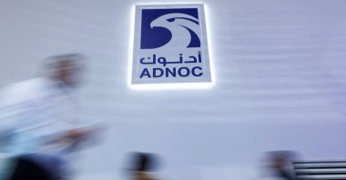 People walk past a logo of Abu Dhabi National Oil Company (ADNOC) during the annual energy industry event Abu Dhabi International Petroleum Exhibition and Conference (ADIPEC), Abu Dhabi, UAE, Nov. 3, 2025. (Reuters Photo)