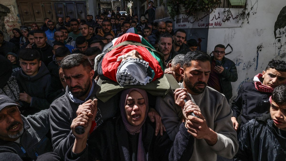 Hanan, the mother of Adam, a 15-year-old Palestinian who was killed by Israeli security forces in the al-Dheisheh refugee camp near the occupied West Bank city of Bethlehem, carries her son's body during his funeral, March 28, 2026. (AFP File Photo)