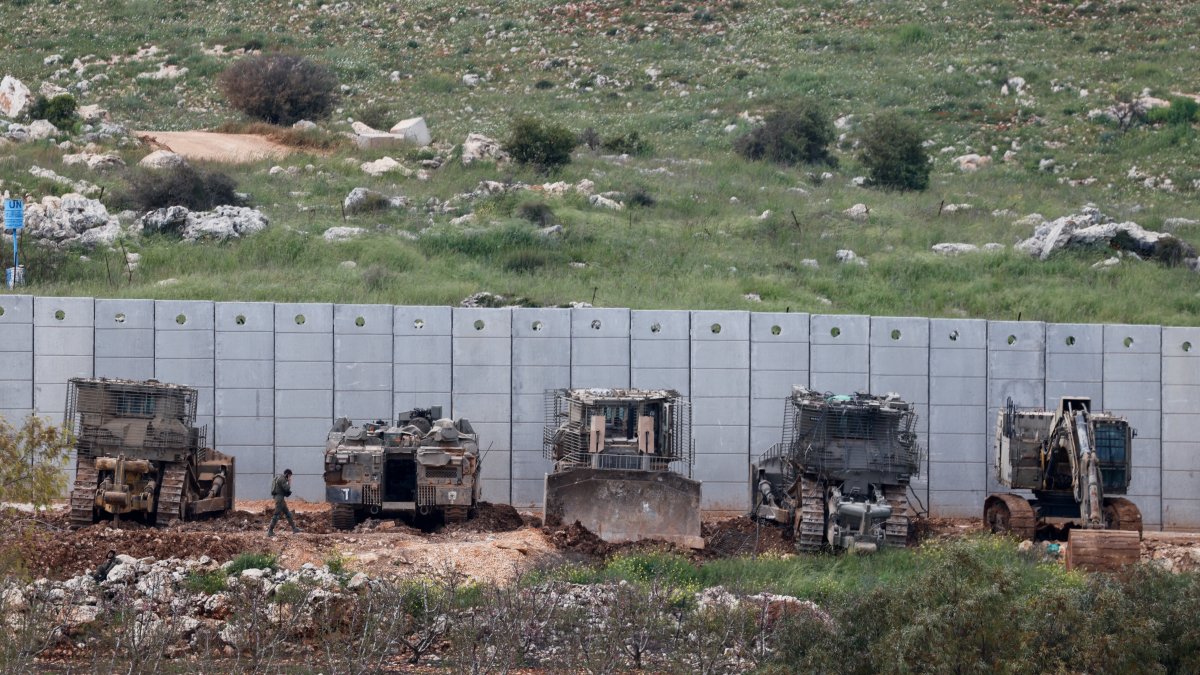An Israeli soldier walks near armored military engineering vehicles on the Israeli side of the border, April 12, 2026. (Reuters Photo)