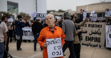 A protestor wearing a face mask of Israeli Prime Minister Benjamin Netanyahu holds a banner that reads "war is an asset" during an anti-war protest, Tel Aviv, Israel, March 14, 2026. (AFP Photo)