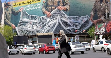 A woman walks past a giant billboard reading 'The Strait of Hormuz remains closed' at the Revolution Square in Tehran, Iran, April 12, 2026. (AFP Photo)