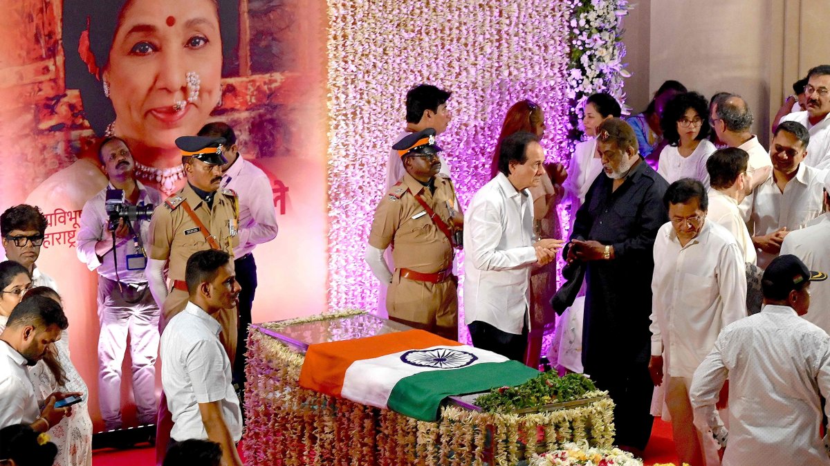 An Indian national flag is placed on the glass casket of late Bollywood playback singer Asha Bhosle as people pay their respects at her residence, Mumbai, India, April 13, 2026. (AFP Photo)