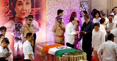 An Indian national flag is placed on the glass casket of late Bollywood playback singer Asha Bhosle as people pay their respects at her residence, Mumbai, India, April 13, 2026. (AFP Photo)