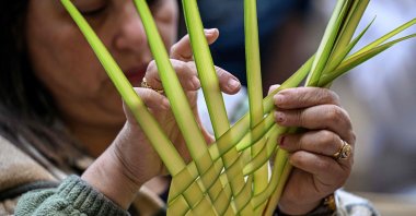 A Christian worshipper arranges a palm frond during mass at the Cave Church at the Coptic Orthodox Monastery of Simon the Tanner in the eastern hillside on Orthodox Palm Sunday, Mokkatam district, Cairo, Egypt, April 5, 2026. (AFP Photo)
