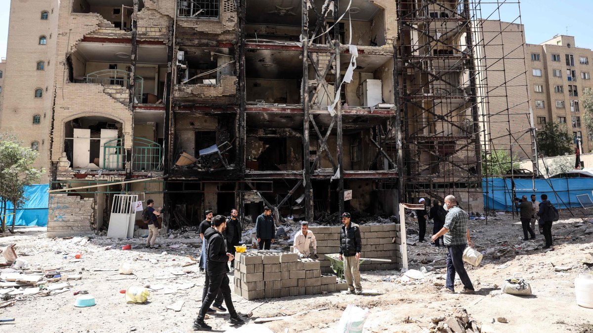 Workers and journalists stand in front of a residential building hit by U.S.-Israel airstrikes days before a two-week ceasefire between Iran and the United States took effect, at the Shahid Broujerdi residential complex in southern Tehran, Iran, April 14, 2026. (AFP Photo)