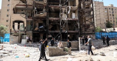 Workers and journalists stand in front of a residential building hit by U.S.-Israel airstrikes days before a two-week ceasefire between Iran and the United States took effect, at the Shahid Broujerdi residential complex in southern Tehran, Iran, April 14, 2026. (AFP Photo)