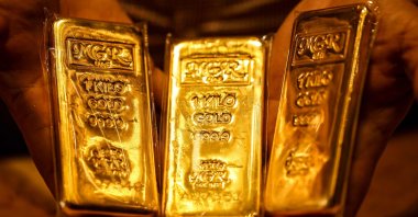An Emirati gold dealer holds bars of gold in a shop in the Dubai Gold Souk, April 13, 2025. (AFP Photo)