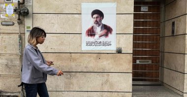 An Iranian woman walks past a poster featuring a portrait of Iran’s new Supreme Leader Mojtaba Khamenei, Tehran, Iran, April 13, 2026. (AFP Photo)