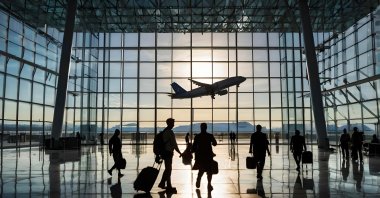 Silhouettes of passengers in a glass airport building. (Shutterstock Photo)
