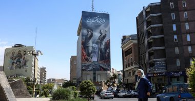 A woman walks past a large billboard referring to the Strait of Hormuz, Tehran, Iran, April 15, 2026. (AFP Photo)
