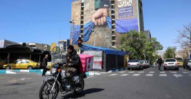 A man rides past a large billboard referring to the Strait of Hormuz at Vanak Square in Tehran, Iran, April 15, 2026. (AFP Photo)