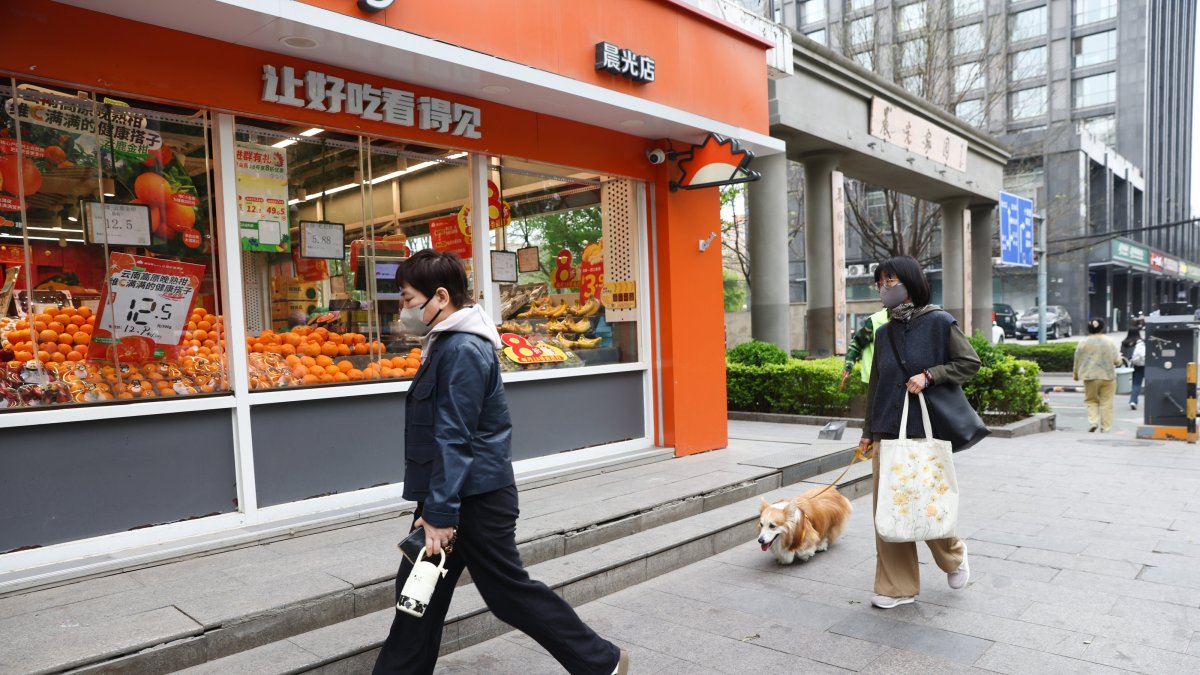 People walk in front of a fruit shop, Beijing, China, April 14, 2026. (EPA Photo)