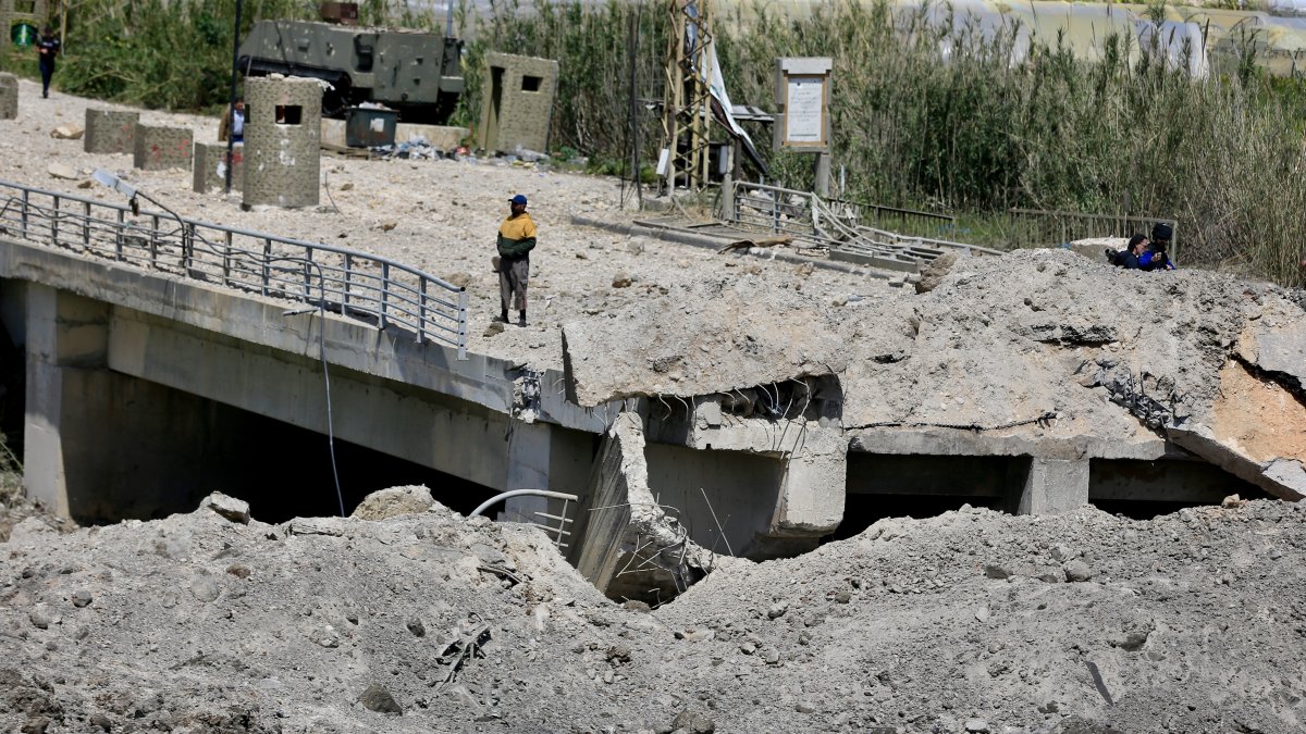 A man stands on a damaged part of the Qasmiyeh Bridge that was targeted by an Israeli airstrike near Tyre, southern Lebanon, April 16, 2026. (EPA Photo)