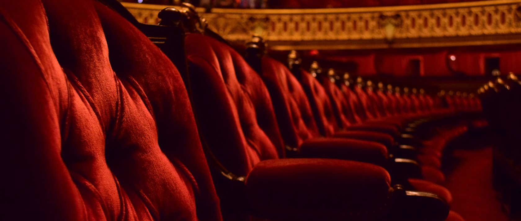 Rows of plush red velvet opera chairs with ornate gold trim. (Getty Images Photo)