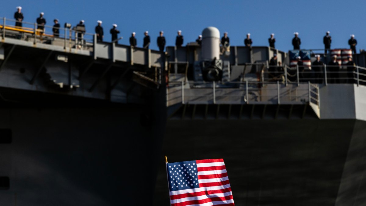 An American Flag is waved as sailors man the rails while the USS George H.W. Bush (CVN 77) prepares to pull away from Naval Station Norfolk, Norfolk, U.S., March 31, 2026. (AP Photo)