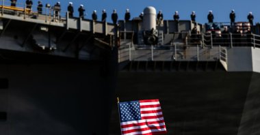 An American Flag is waved as sailors man the rails while the USS George H.W. Bush (CVN 77) prepares to pull away from Naval Station Norfolk, Norfolk, U.S., March 31, 2026. (AP Photo)