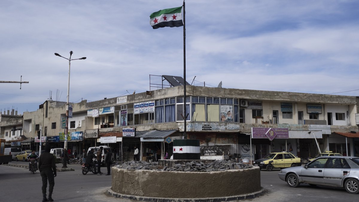 Cars drive past a roundabout hoisting the Syrian flag in Salam City, Quneitra, Syria, Jan. 5, 2025. (AP Photo)