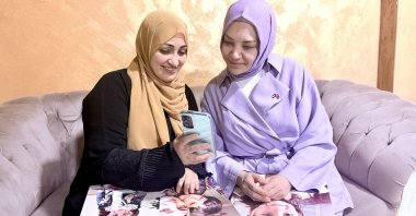 Rania (L) shows their family photos to Daily Sabah columnist Hilal Kaplan. (Courtesy of Hilal Kaplan)