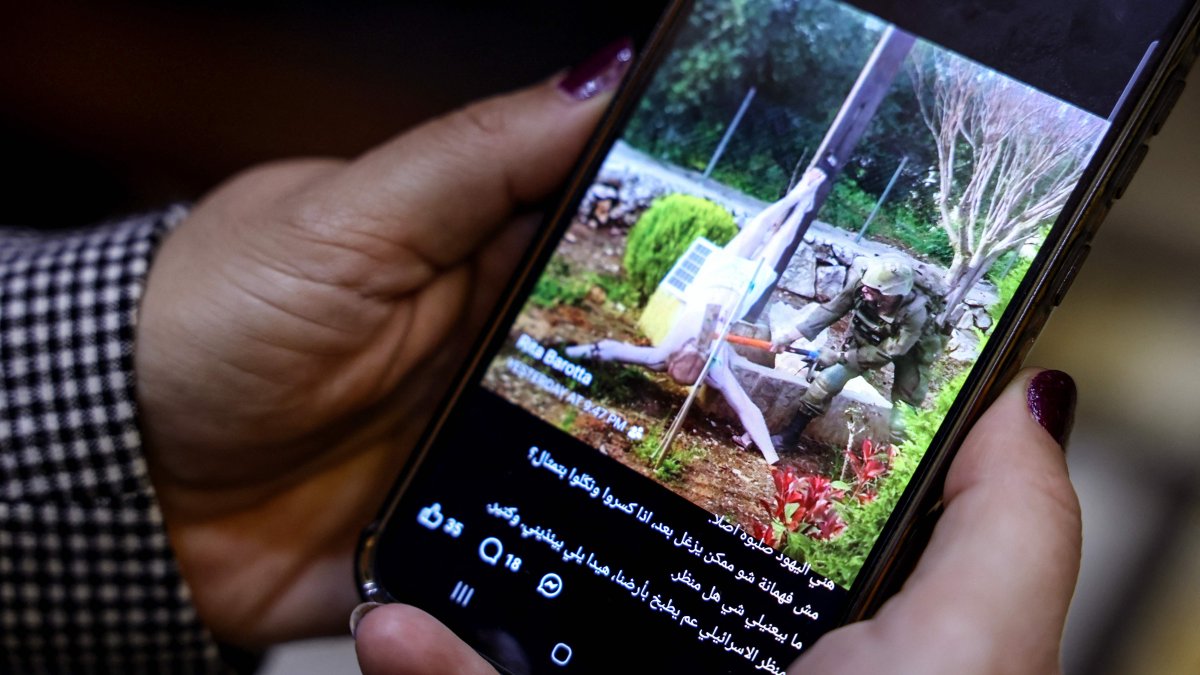 A woman checks a social media post on her mobile phone featuring an image that appears to show an Israeli soldier hitting a statue of Jesus Christ in the southern Lebanese Christian village of Debl, in Beirut, Lebanon, April 20, 2026. (AFP Photo)