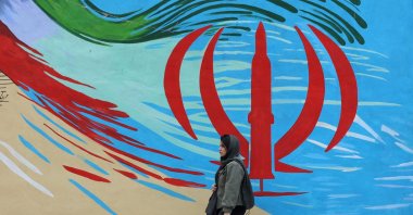 An Iranian woman walks next to a wall painting of Iran’s national flag on a street, Tehran, Iran, April 20, 2026. (EPA Photo)