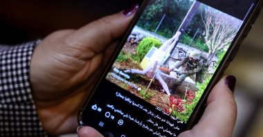 A woman checks a social media post on her mobile phone featuring an image that appears to show an Israeli soldier hitting a statue of Jesus Christ in the southern Lebanese Christian village of Debl, in Beirut, Lebanon, April 20, 2026. (AFP Photo)
