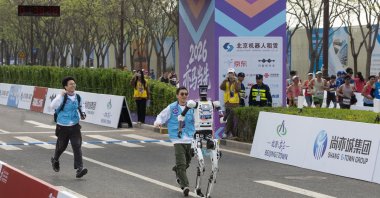 Handlers catch up to their humanoid robot at the finish line at the second Beijing E-Town Half Marathon and Humanoid Robot Half Marathon, a half-marathon run by humans and humanoid robots, Beijing, China, April 19, 2026. (EPA Photo)