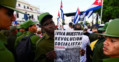 A member of the Ministry of the Interior holds a poster reading "Long live our socialist revolution" during celebrations marking the victory on the 65th anniversary of the Bay of Pigs invasion and the declaration of the socialist character of the Cuban Revolution in Havana, Cuba, April 16, 2026. (AFP Photo)
